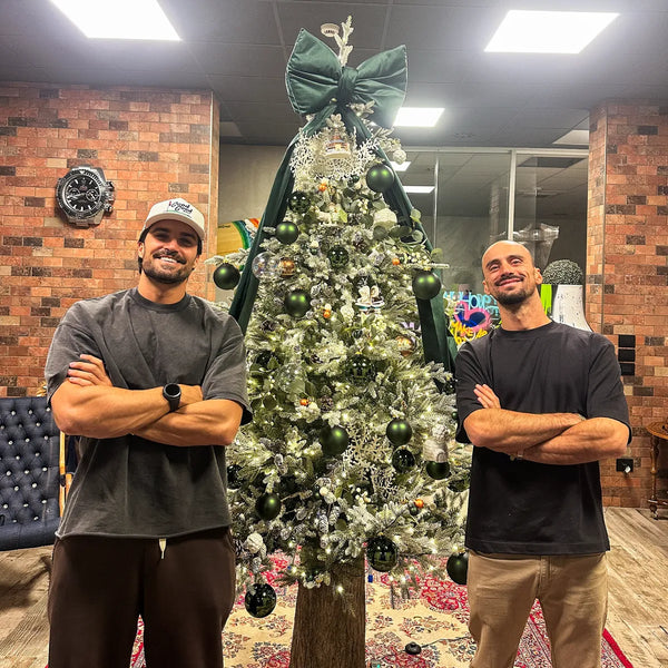 Albero di Natale con fiocco verde e decorazioni argento allestito da Varzi in uno spazio con pareti in mattoni