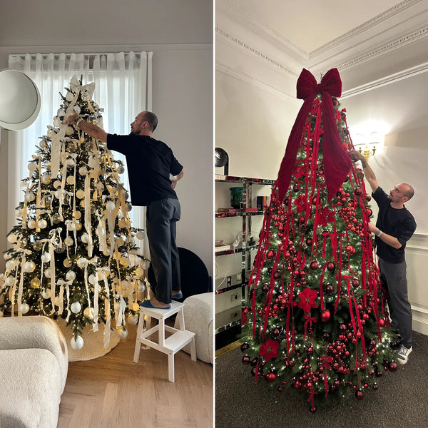 Due alberi di Natale durante l'allestimento, uno bianco e oro e uno rosso con grande fiocco