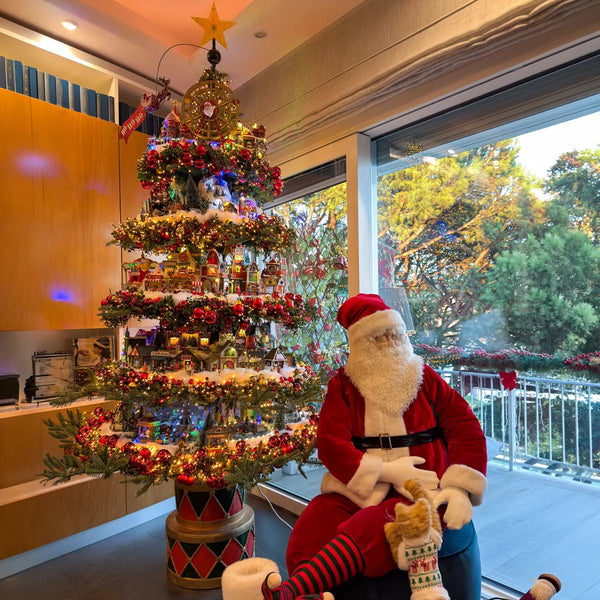 Albero di Natale a cerchi con Babbo Natale gigante accanto a una vetrata