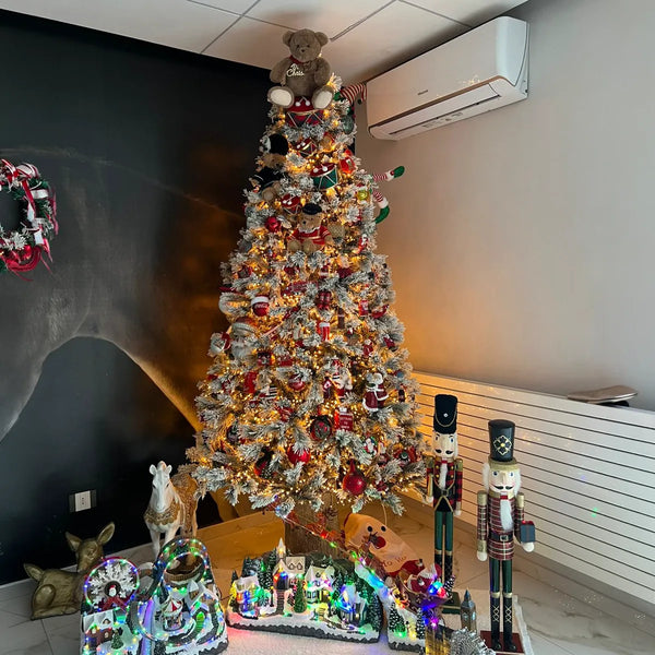 Albero di Natale innevato con schiaccianoci e villaggio natalizio illuminato