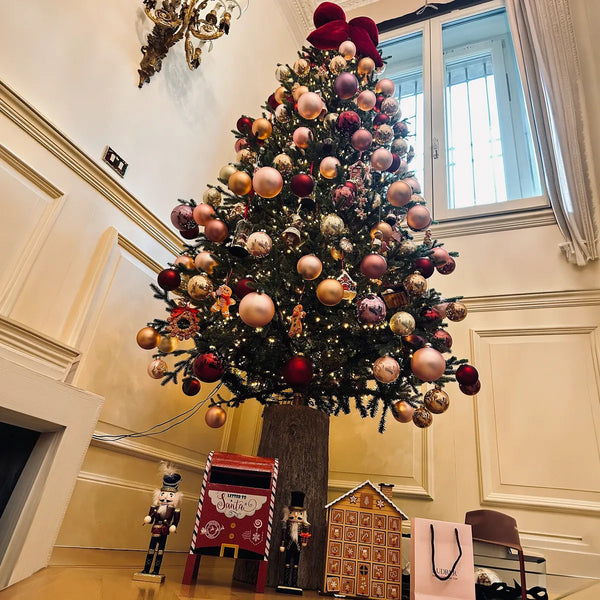 Albero di Natale con palline bordeaux, rosa e oro in un ambiente classico