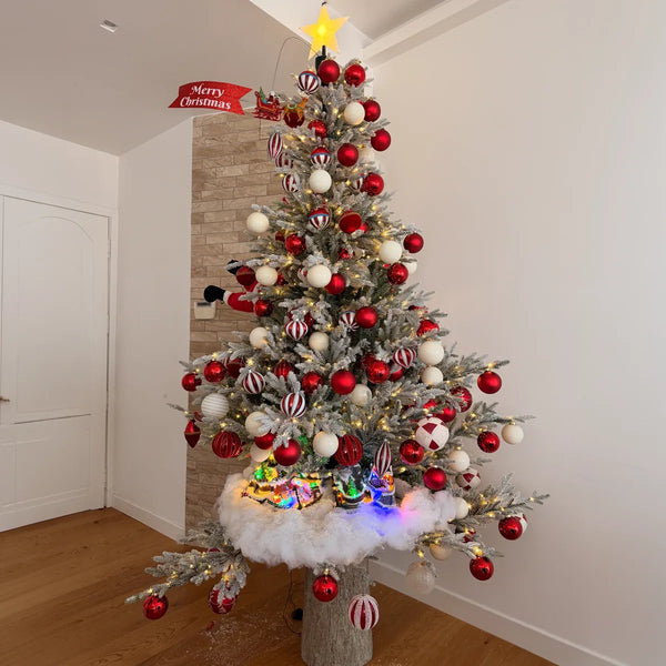 Albero di Natale innevato con palline rosse e insegna Merry Christmas